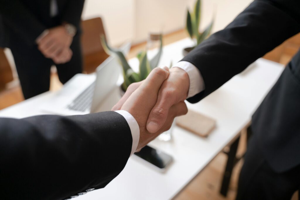 pexels-photo-5520322-5520322 Close-up of a handshake between two professionals in a business setting, symbolizing agreement.